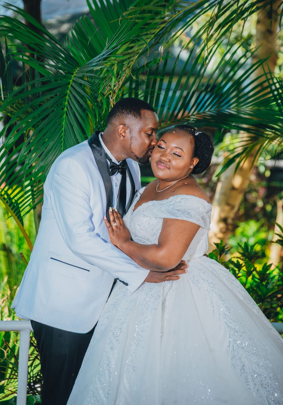 A bride and groom embracing among palms at their wedding in Kenya